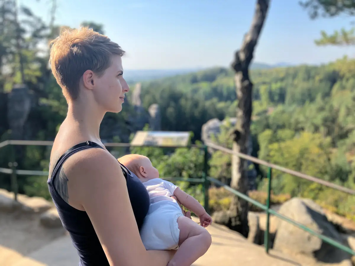 Maminka a zároveň laktační poradkyně nese v rukou miminko.